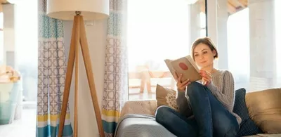 En dame sitter i en sofa og leser bok