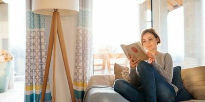 En dame sitter i en sofa og leser bok