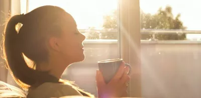 En dame i profil holder en kopp kaffe